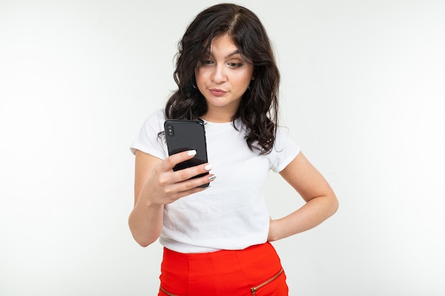 Brunette girl is surfing the internet holding a phone in her hands