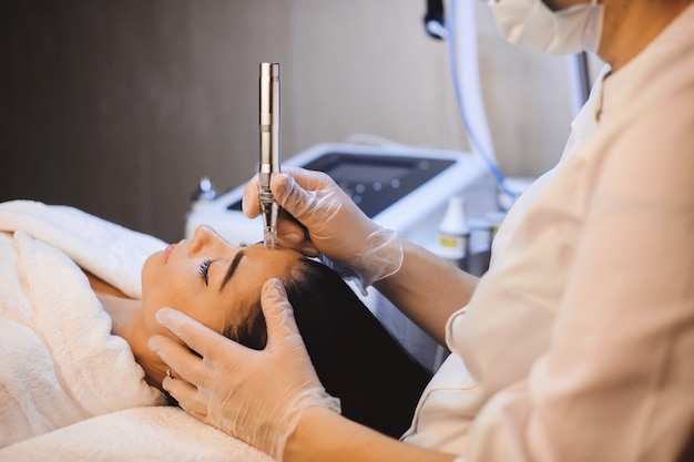 Brunette  girl lying on the couch while having a spa procedure for her facial skin