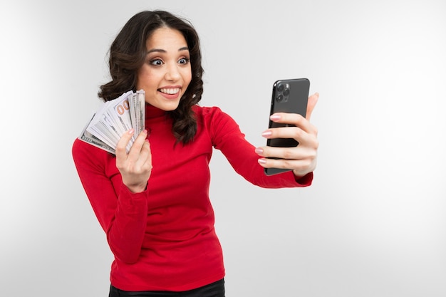 Brunette girl makes selfie with money in her hands with copy space