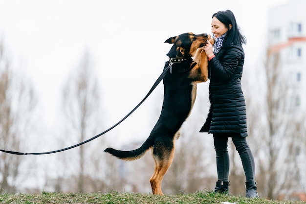 Photo brunette girl playing with dog outdoors