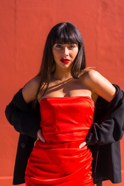 Brunette girl in a portrait on a red background red dress provocative girl