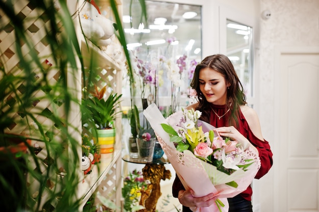 Брюнетка девушка в красном купить цветы в цветочном магазине.