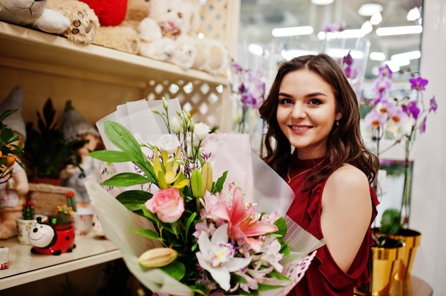 Brunette girl in red buy flowers at flower store.