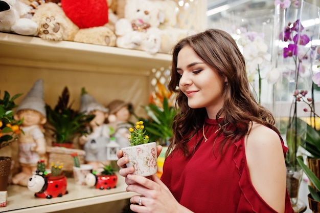 Brunette girl in red buy flowers at flower store.