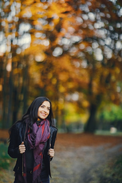 brunette girl relaxing at the park during autumn