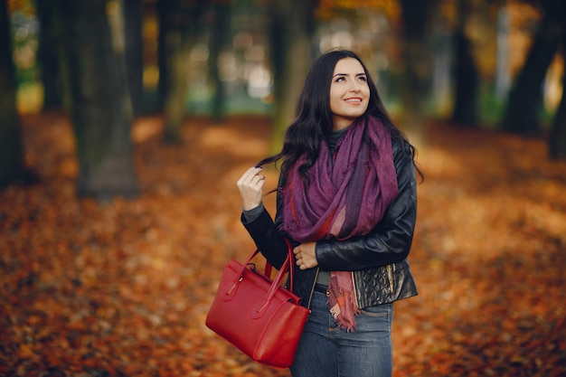 brunette girl relaxing at the park during autumn