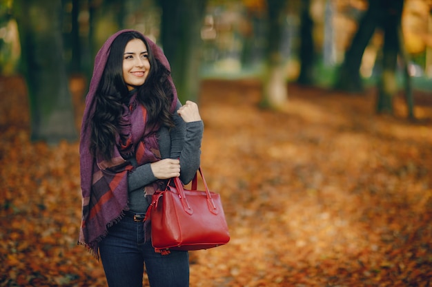 brunette girl relaxing at the park during autumn