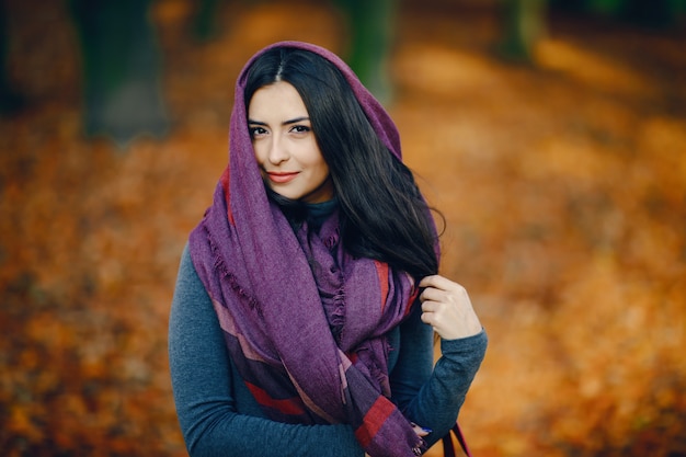 brunette girl relaxing at the park during autumn