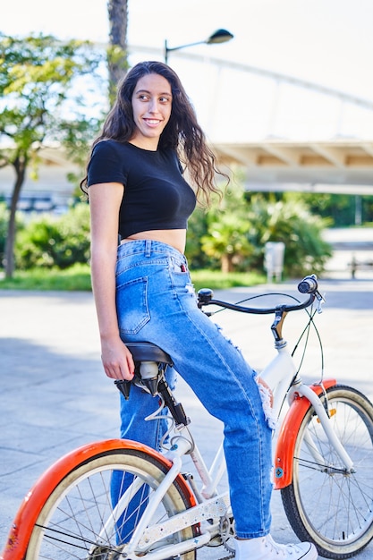 Девушка брюнетка, езда на велосипеде в городе