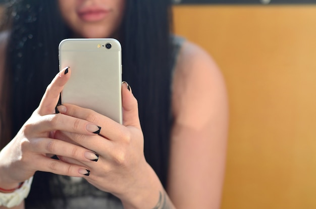 The brunette girl uses a modern touch smartphone