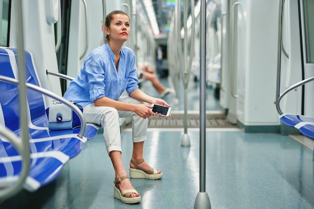 Девушка брюнет с помощью мобильного телефона в метро.