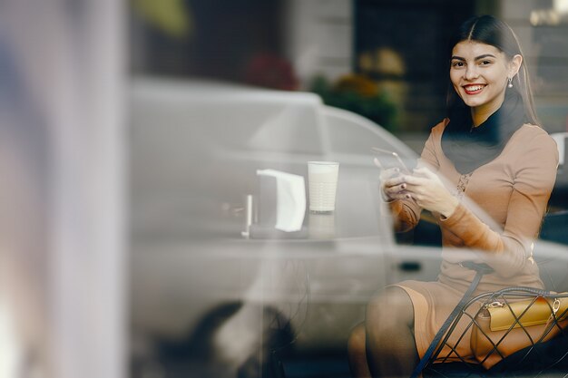 brunette girl using her cell phone while sitting at a rastaurant for lunch