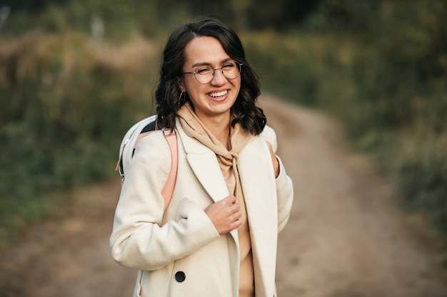 brunette girl with backpack on the forest path