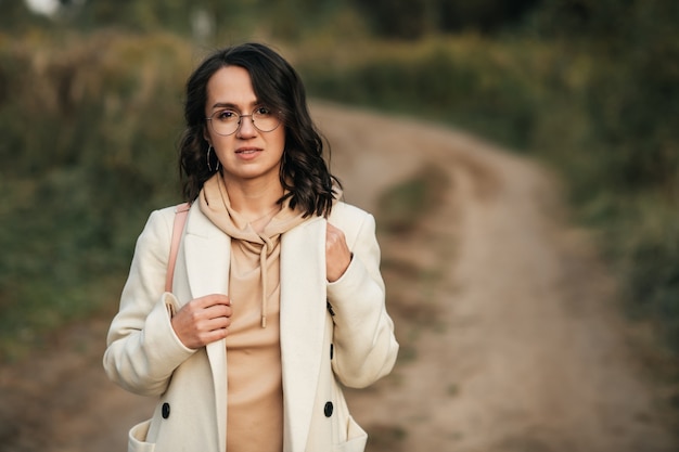 brunette girl with backpack on the forest path