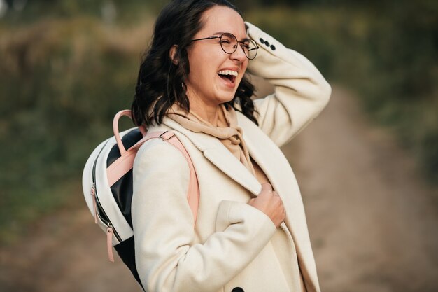 brunette girl with backpack on the forest path