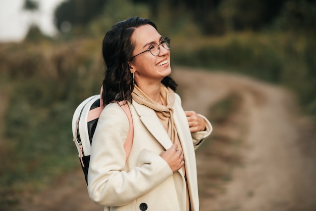 Photo brunette girl with backpack on the forest path