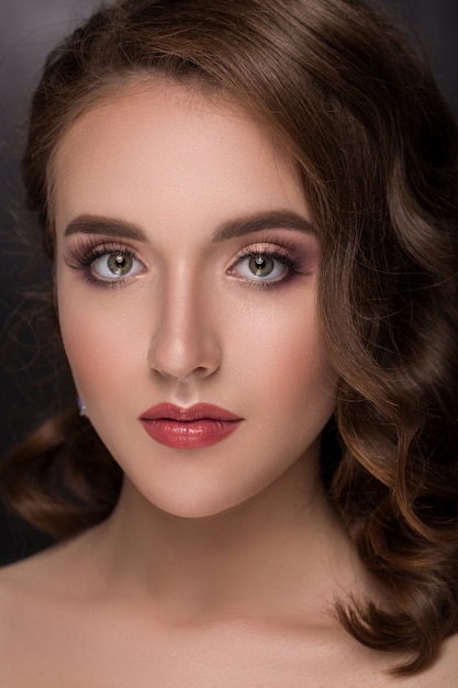 Brunette girl with long and shiny curly hair .