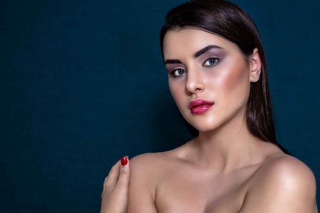 Brunette girl with long and shiny long hair and with perfect make-up on a blue background.