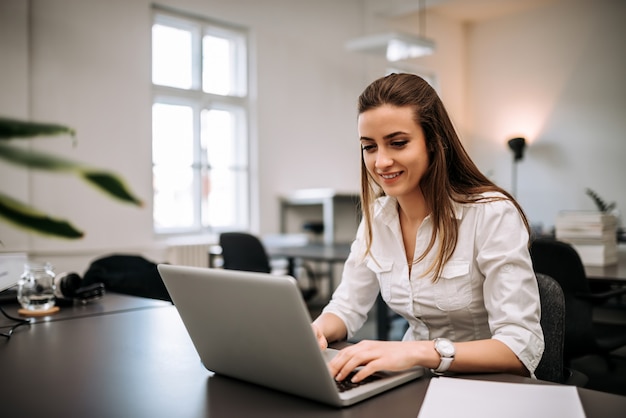 Brunette girl working in large office.