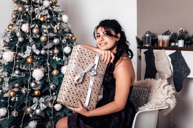 Brunette glimlachende gelukkige vrouw die verpakte geschenkdoos van lint opent