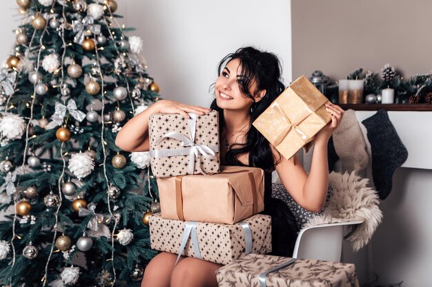 Brunette glimlachende gelukkige vrouw die verpakte geschenkdoos van lint opent