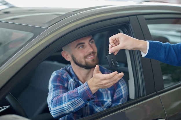 Brunette guy getting key from manager after buying vehicle