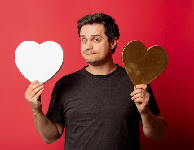 Brunette guy with two heart shapes on red space