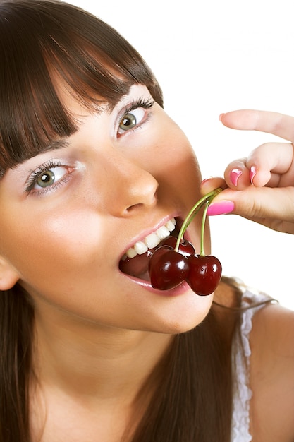 Brunette holding cherryes, close up, looking at camera, studio on white