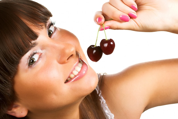 Brunette holding cherryes, close up, looking at camera, studio on white