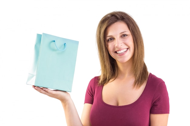 Brunette holding a gift bag smiling at camera