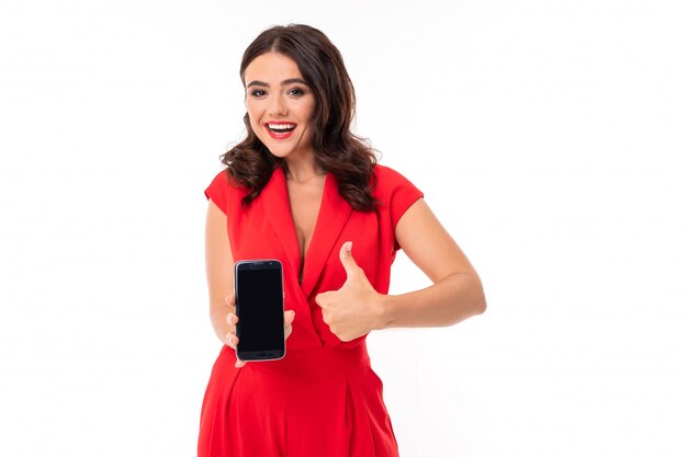 Brunette holding a phone in her hands on a white isolated , with a wide smile shows a gesture of super