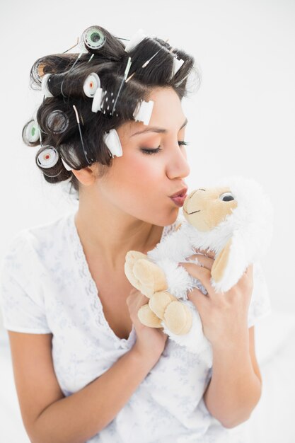 Brunette in haarrollen die schapen teddy kussen