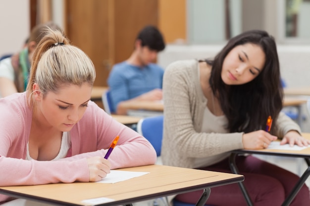 Brunette is trying to copy blonde student in exam