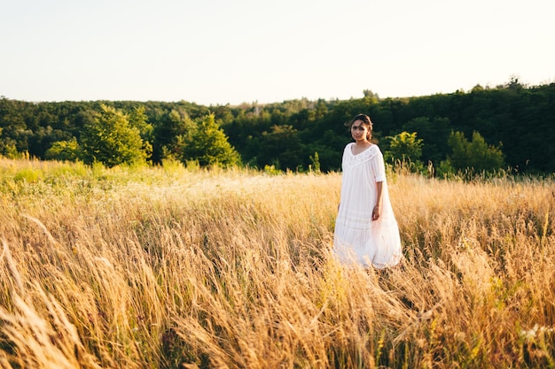 Brunette jonge vrouw in wild veld Natuurlijke schoonheid en romantiek concept Zonsondergang licht Uitzicht vanaf de achterkant