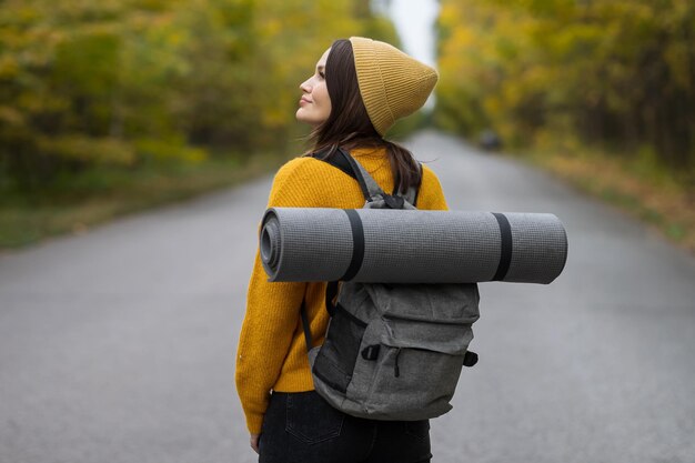 Brunette lady looks away hitchhiking alone with backpack