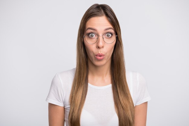 brunette lady with glasses posing against the white wall