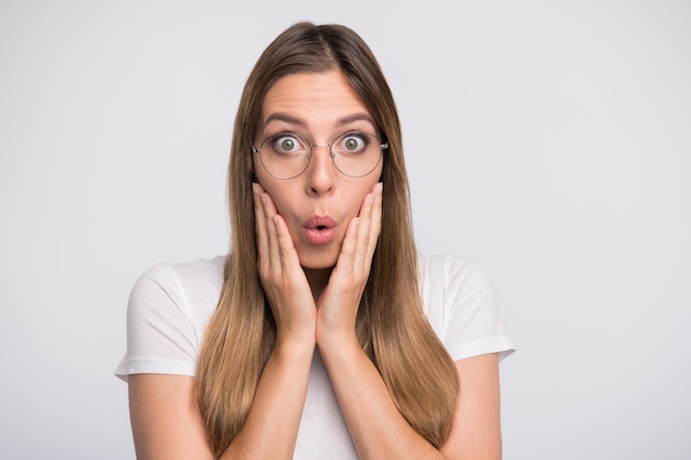 brunette lady with glasses posing against the white wall