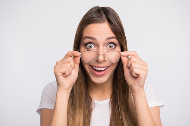 brunette lady with glasses posing against the white wall