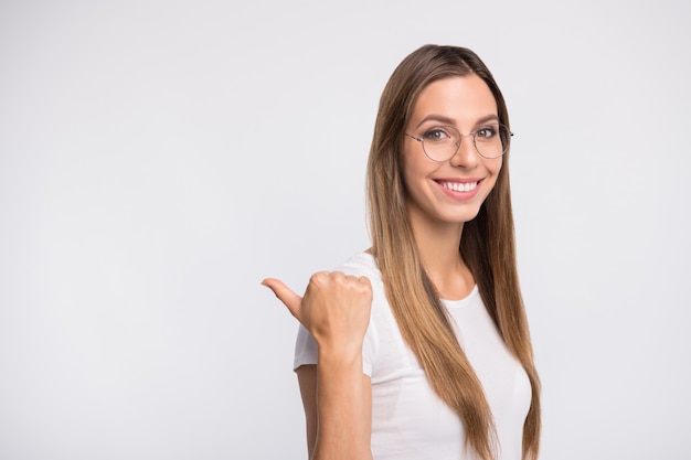 brunette lady with glasses posing against the white wall