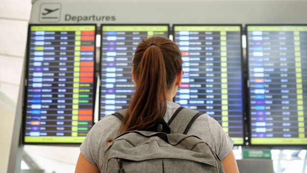 Brunette looks at departures schedule in airport terminal