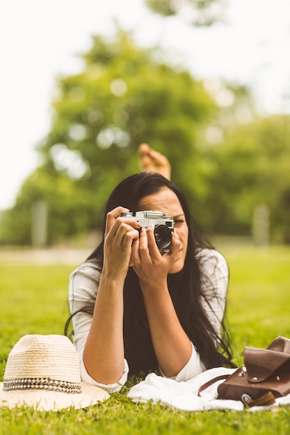 Foto brunette che si trova sull'erba che cattura foto