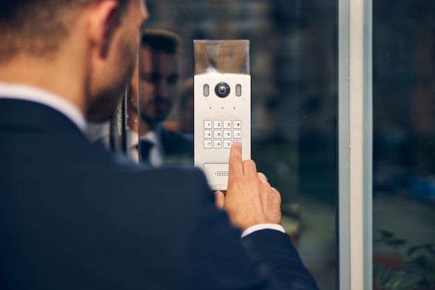 Photo brunette male in official clothes staing outside while pressing key for door to open