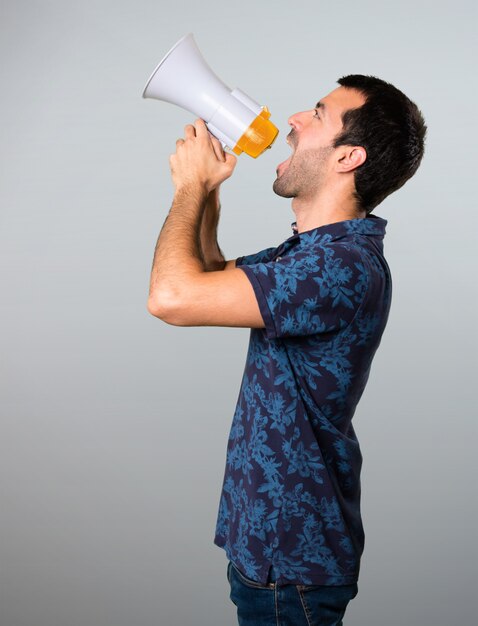 Brunette man holding a megaphone on grey background