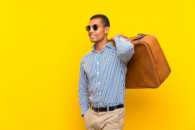 Brunette man holding a vintage briefcase over isolated yellow background