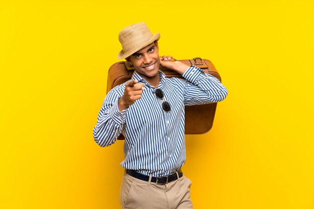 Brunette man holding a vintage briefcase pointing with a confident expression