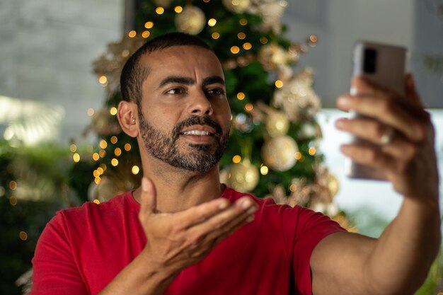 brunette man in een rood shirt praten op video-oproep op zijn smartphone