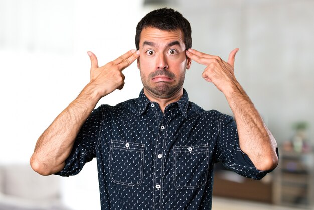 Brunette man making suicide gesture inside house