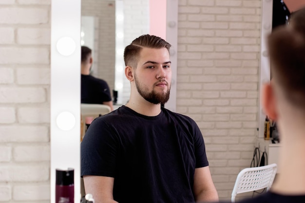 Brunette man met stijlvol kapsel op kapperszaak achtergrond