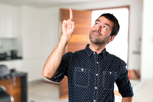 Brunette man pointing up inside house