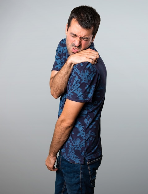 Brunette man with shoulder pain on grey background